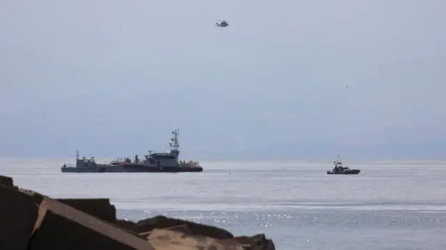 A helicopter and boats off the Sicilian coast