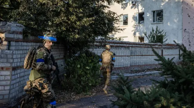 Ukrainian soldiers walk in the Ukrainian controlled city of Sudzha on August 18th 2024, in Kursk Region, Russia. Ukrainian forces operating in Russia's Kursk Region have destroyed a second key bridge, Commander of Ukrainian Air Force said, as they attempt to push further into Russia.