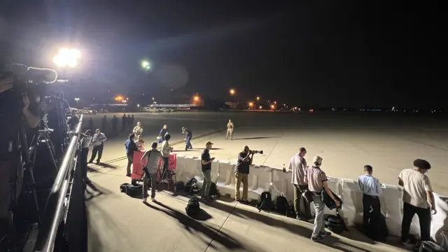 Media waiting on the tarmac for a plane with freed prisoners on board