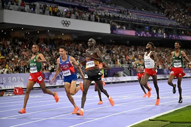 Joshua Cheptegei (R) crosses the finish line followed by second-paced Ethiopia's Berihu Aregawi