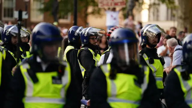 Police officers look on as people attend the 'Enough is Enough' protest in central London on 31 July