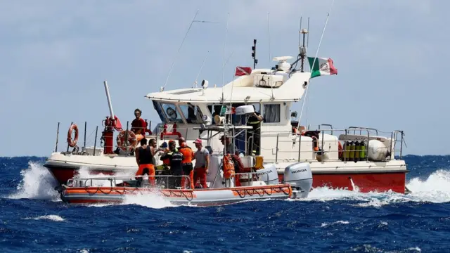 A large fire service boat next to a smaller boat, which has divers on board