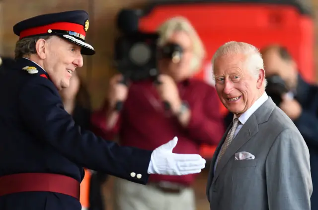 King Charles III reacts as he is greeted upon arrival to visit Southport Community Fire Station