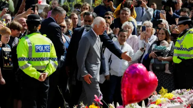 King Charles stands near tributes laid to the victims of the Southport attack