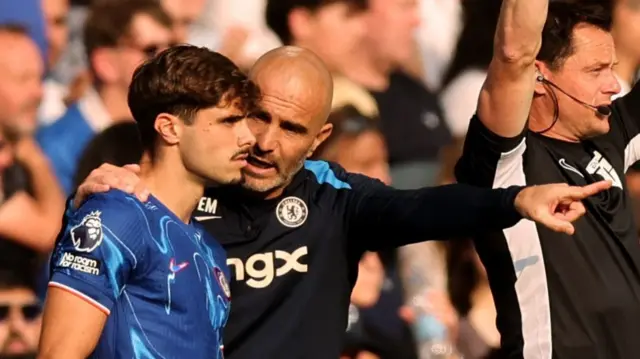 Chelsea manager Enzo Maresca speaks to Pedro Neto as he waits to come on against Manchester City