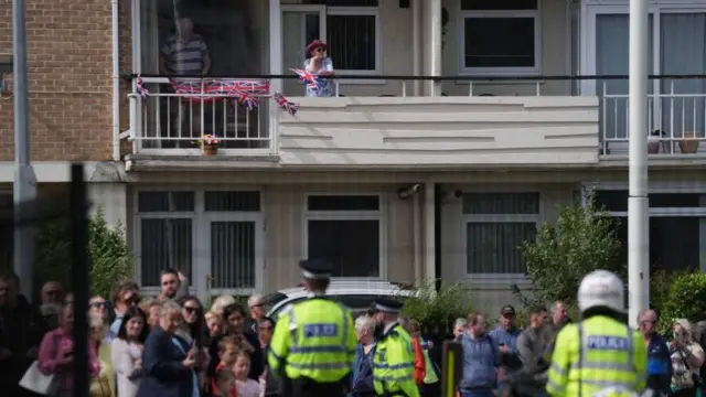 A man and a woman on a balcony with flags