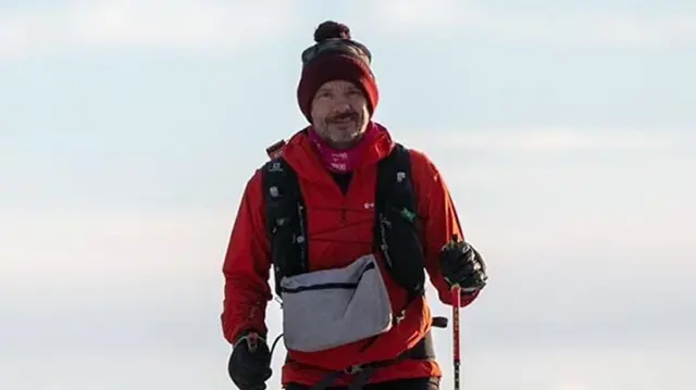 Stephen Chamberlain wearing a red coat and bobble hat