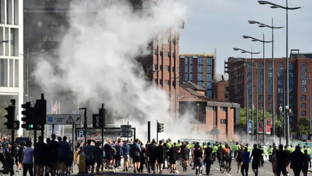 Smoke billows as police officers face protesters in Liverpool on 3 August 3