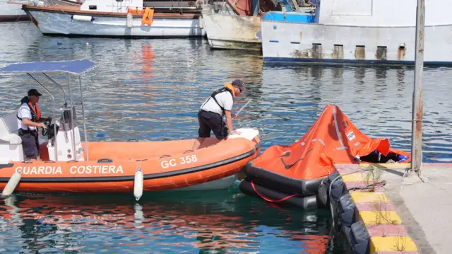 Two members of search and rescue team in orange coastguard boat off the coast of Sicily