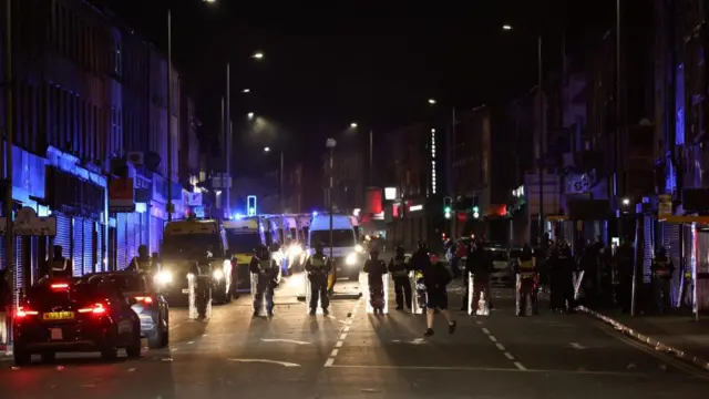 Riot police are positioned near the scene of a violent disorder on County Road in Liverpool, Britain