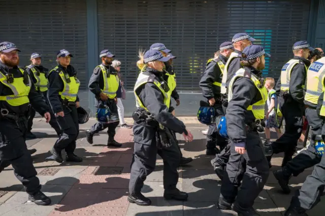 A large group of police walk down a footpath