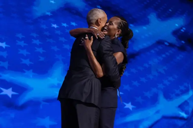 Former US President Barack Obama greets former US First Lady Michelle Obama on stage before delivering remarks during the second night of the Democratic National Convention