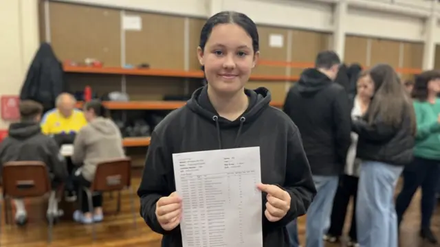 Poppy holds up her results after collecting them at school