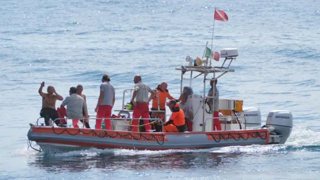 Rescuers sit in a boat during a search and rescue operation in Porticello, Italy