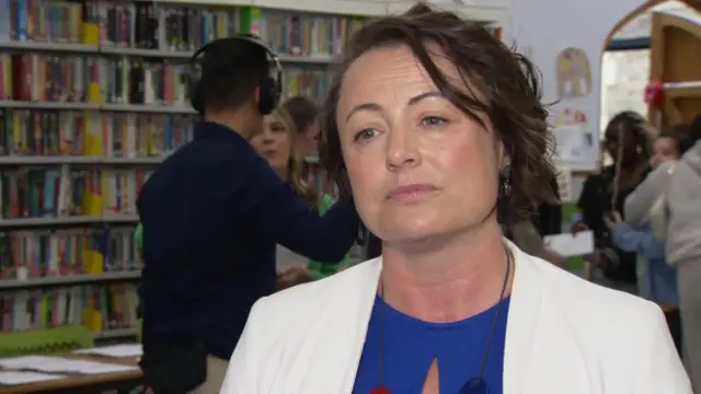 Catherine McKinnell speaks to a reporter just off camera while she visits a school