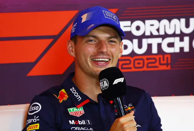 Max Verstappen holds a microphone in the drivers' press conference