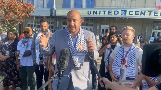 A man talks to reporters with the United Center in the background