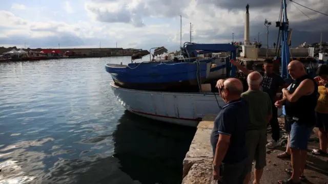 People watch rescue personnel at the scene where a luxury yacht sank, off the coast of Porticello, near the Sicilian city of Palermo, Italy, August 22