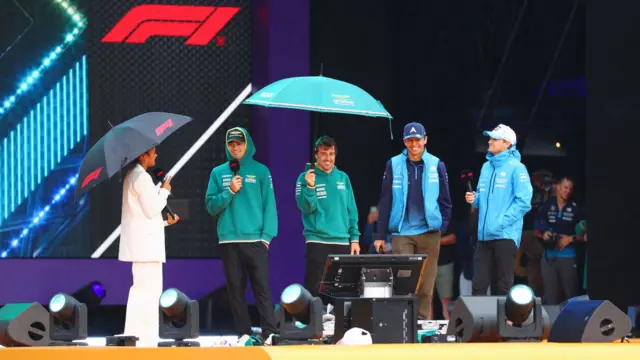 Lance Stroll, Fernando Alonso, Alex Albon and Logan Sargeant in stage in Zandvoort with umbrellas up