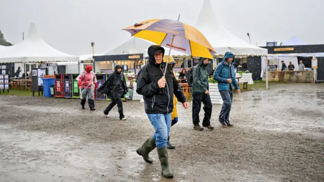 People walk in the rain at the folk music Toender Festival as the Storm Lilian approaches, in Toender, Denmark