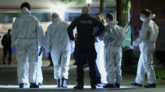 Police members and forensic experts work following an incident in which several individuals were killed on Friday night when a man randomly stabbed passers-by with a knife at a city festival