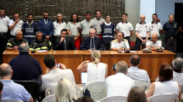 Officials and personnel from the search and rescue operations facing rows of reporters.