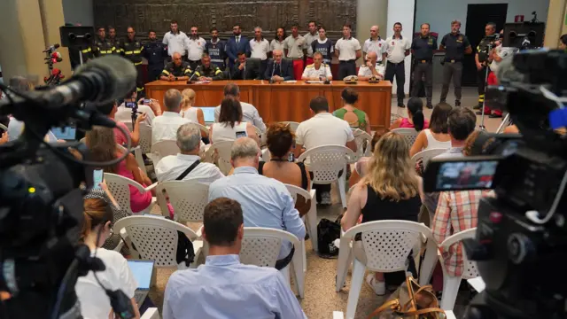 Reporters seated in rows at the press conference.