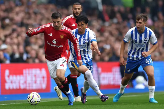 Mason Mount of Manchester United runs with the ball under pressure from Kaoru Mitoma