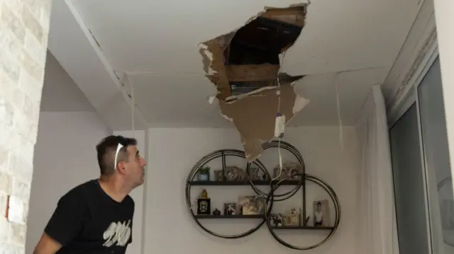 A man inspects the damage of a house after it was hit by a rocket fired from Lebanon on August 25, 2024 in Acre, Israel