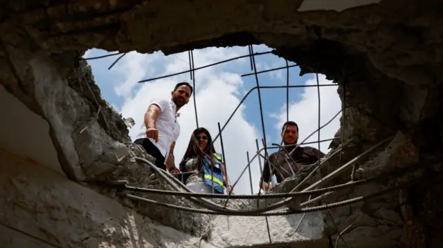 Israelis look at the damage to a building in northern Israel