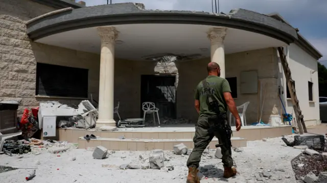 A member of a rapid response team walks by a building in northern Israel which was damaged by the Hezbollah attack