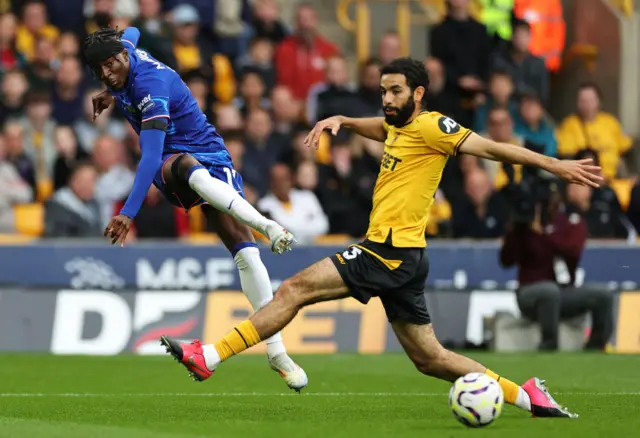 Noni Madueke of Chelsea shoots whilst under pressure from Rayan Ait-Nouri of Wolverhampton Wanderers during the Premier League match between Wolverhampton Wanderers FC and Chelsea FC at Molineux