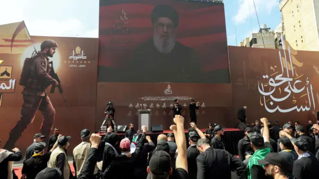 Lebanon's Hezbollah leader Sayyed Hassan Nasrallah appears on a screen as he addresses his supporters