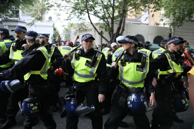 A line of police officers with truncheons at Notting Hill carnival.