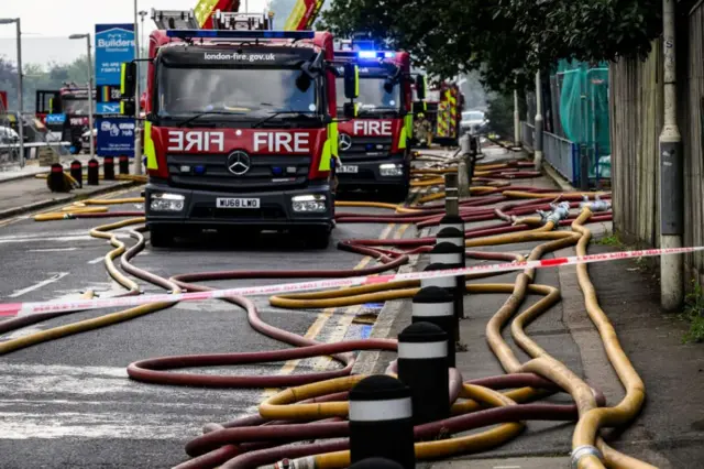 Hoses fill the road as fire teams attempt to extinguish a major fire in an apartment block on August 26