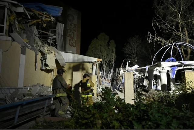 Ukrainian emergency services conduct a search and rescue operation among rubble of a building