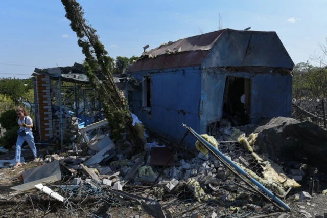 A woman walks next to a residential building damaged during a Russian missile and drone strike