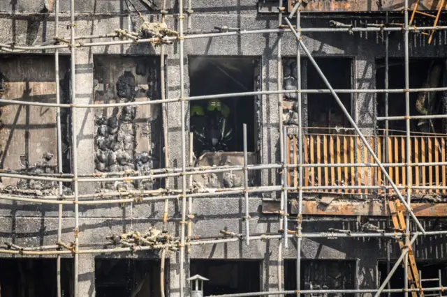 Fire teams are seen inside a destroyed apartment as they attempt to extinguish a major fire in an apartment block on 26 August