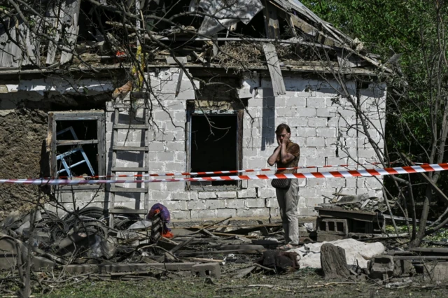 A local resident reacts next to a residential building damaged by a Russian missile strike