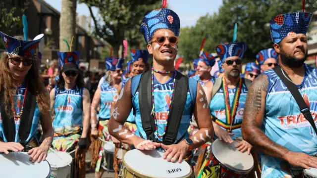 Drummers in blue shirts and hats at Notting Hill Carnival