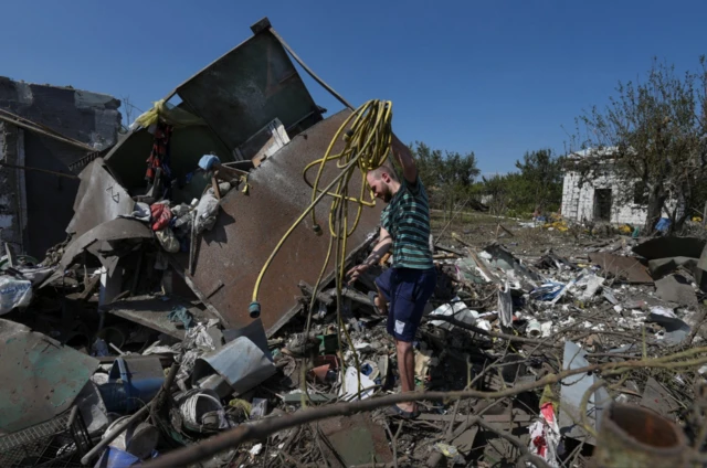 A local resident sorts items next to his house damaged during a Russian missile and drone strike