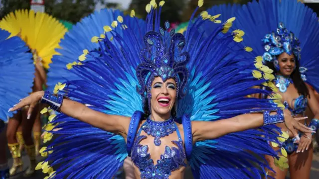 Woman dressed in blue sparkled outfit with large feathered cape