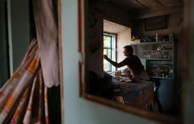 A local woman cleans the debris from windows inside her home