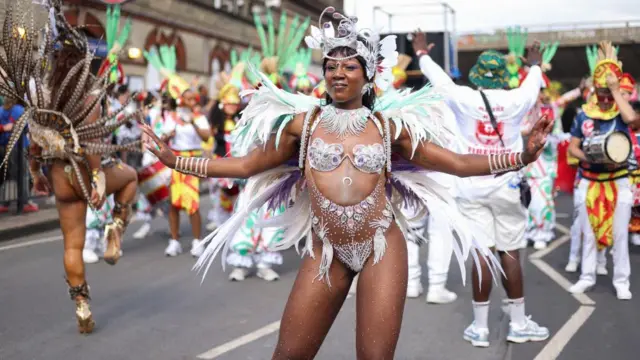 Woman in white and silver carnival outfit adorned with jewels and wings