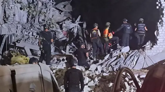 Emergency workers and officials inspect a damaged building