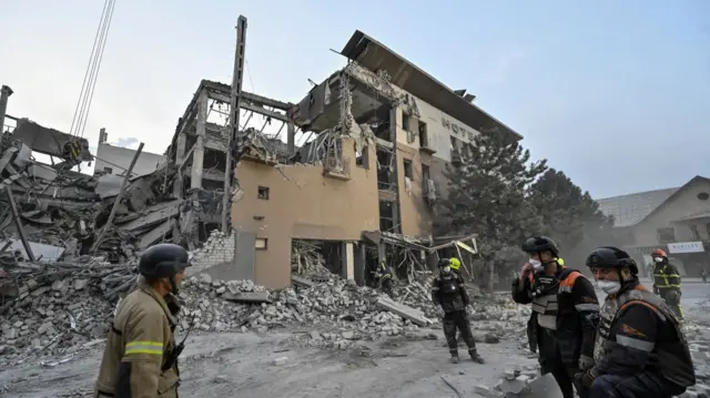 Rescuers stand at a site of a Russian missile strike, amid Russia's attack on Ukraine, in Kryvyi Rih,