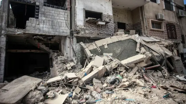 Collapsed part of a building fallen onto the street in Nur Shams camp in Tulkarm with debris and pile of building material with large holes in the structure of the building