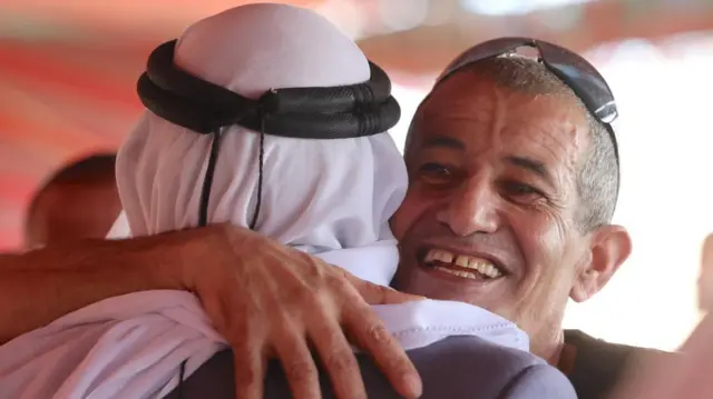 Kaid Farhan Elkadi, a Bedouin Israeli hostage hugging another man on his return with a smile on his face, the other man is turned away from the camera