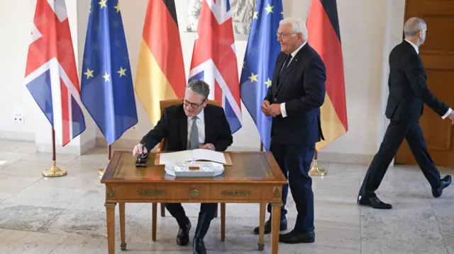 Starmer signs a guestbook with German President Frank-Walter Steinmeier - he's meeting Chancellor Scholz later