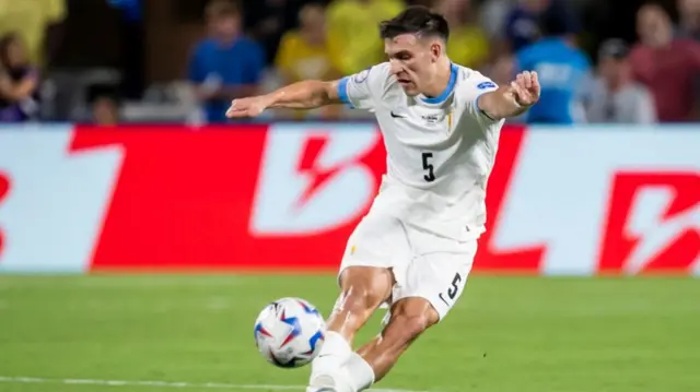 Manuel Ugarte kicking a ball while playing for Uruguay